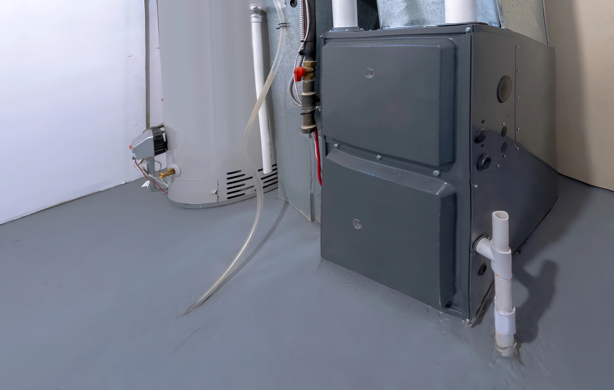 A gray furnace and a white water heater installed in a clean, unfinished basement with visible pipes and ducts.